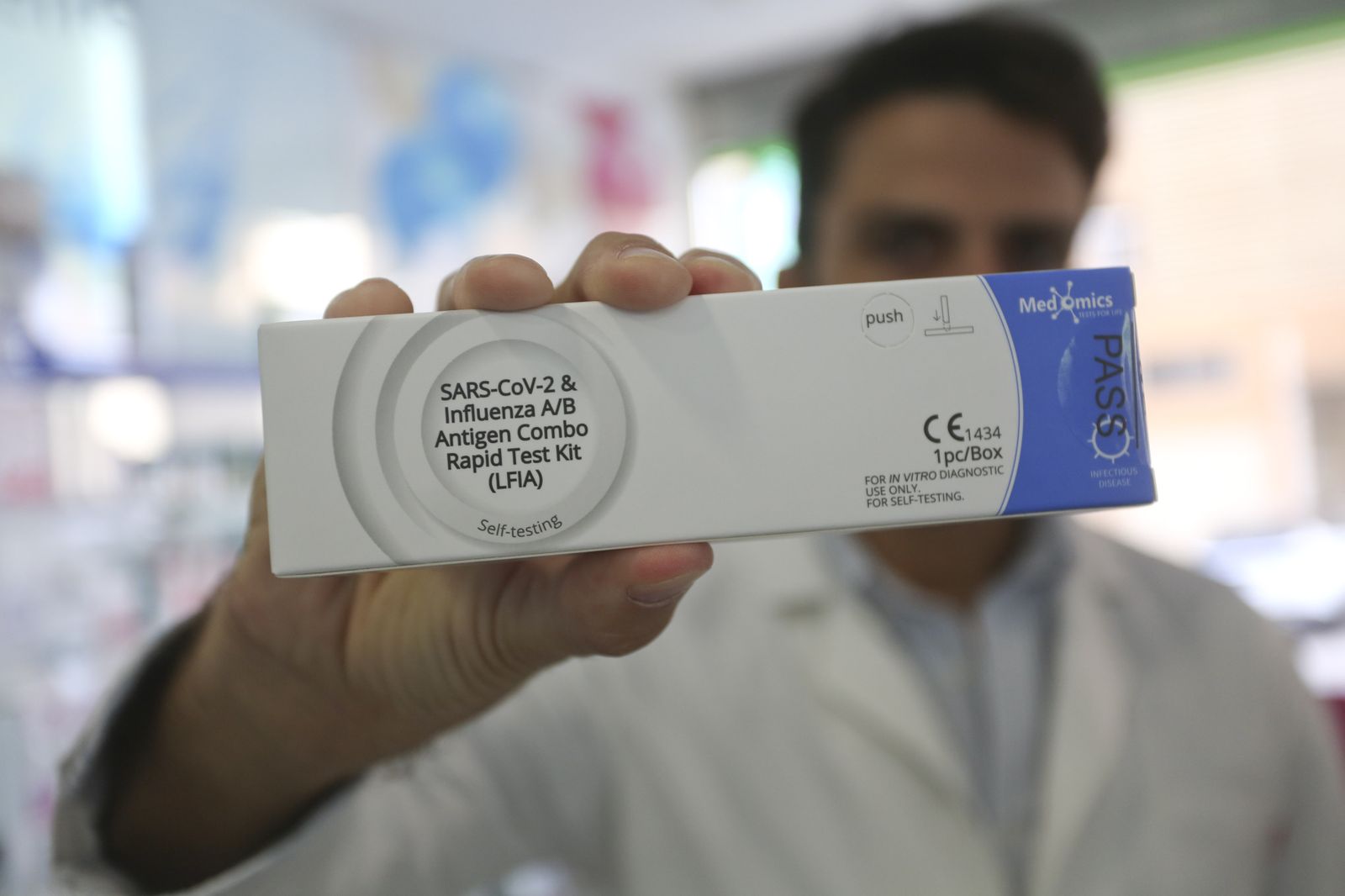 Un profesional de una farmacia de Málaga muestra un test combinado de Covid y gripe.
