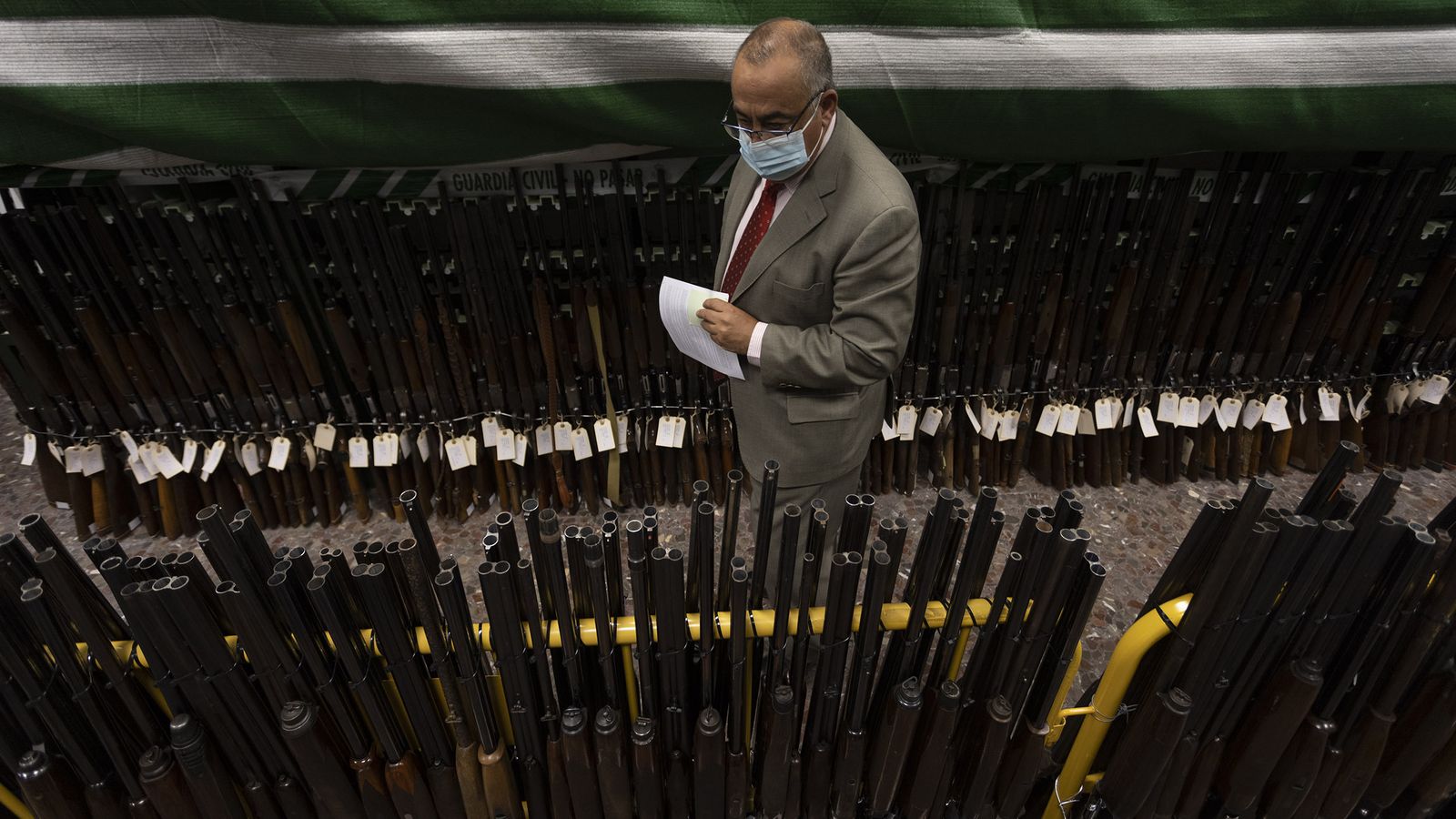 Un hombre observa una serie de escopetas expuestas antes de la subasta.