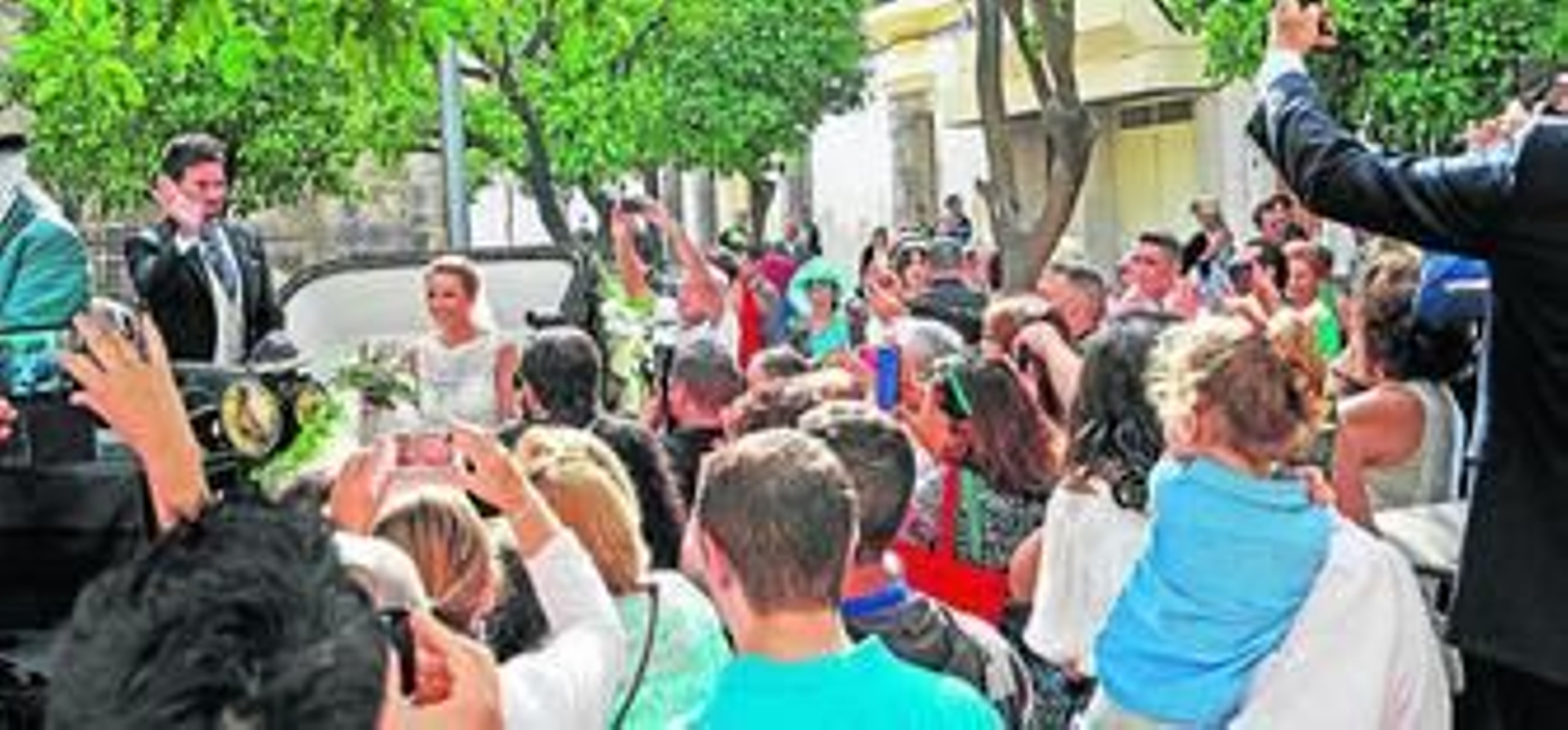 Los novios saludan desde el coche de caballos a los curiosos congregados en la zona, ayer.