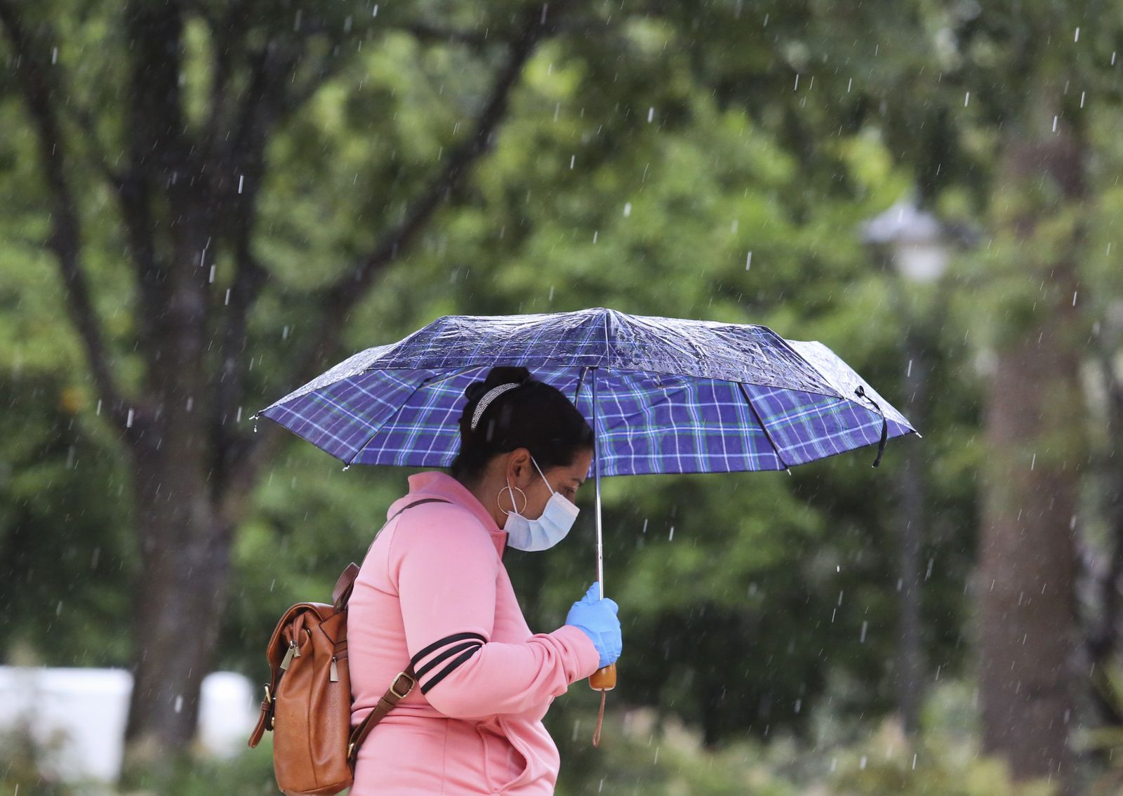 Unas mujer con mascarilla se protege de la lluvia el pasado mes de mayo.