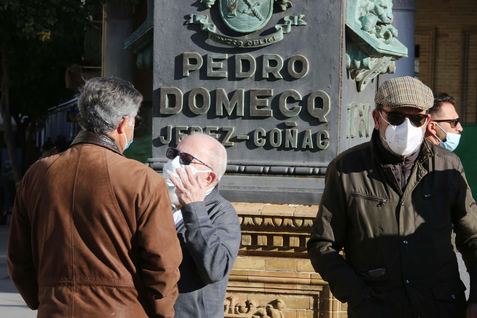 Ciudadanos con la mascarilla  puesta junto al reloj del Gallo Azul.