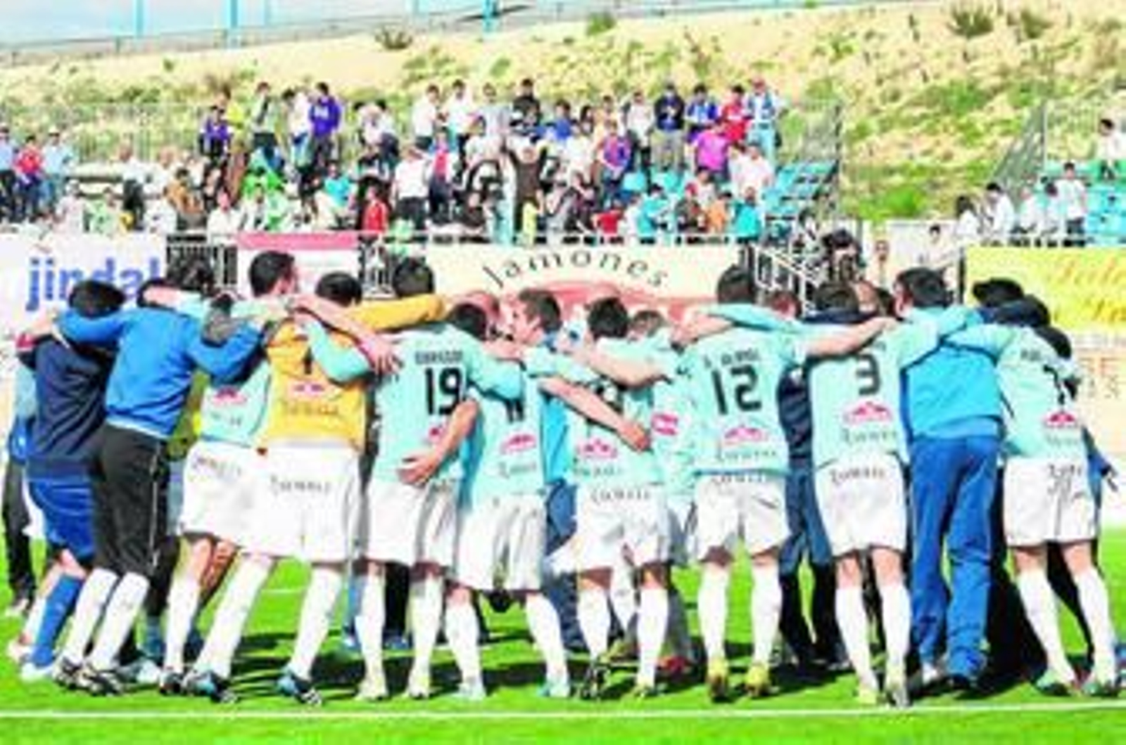 Jugadores, técnicos y auxiliares del Lucena celebran sobre el césped la clasificación matemática, el sábado.