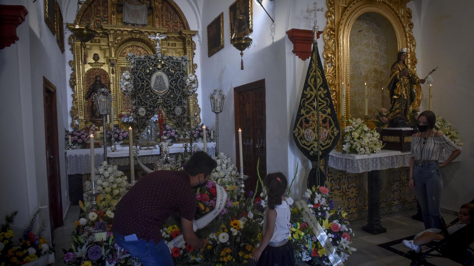 Una niña deposita un ramo de flores a los pies del Simpecado de Gines.