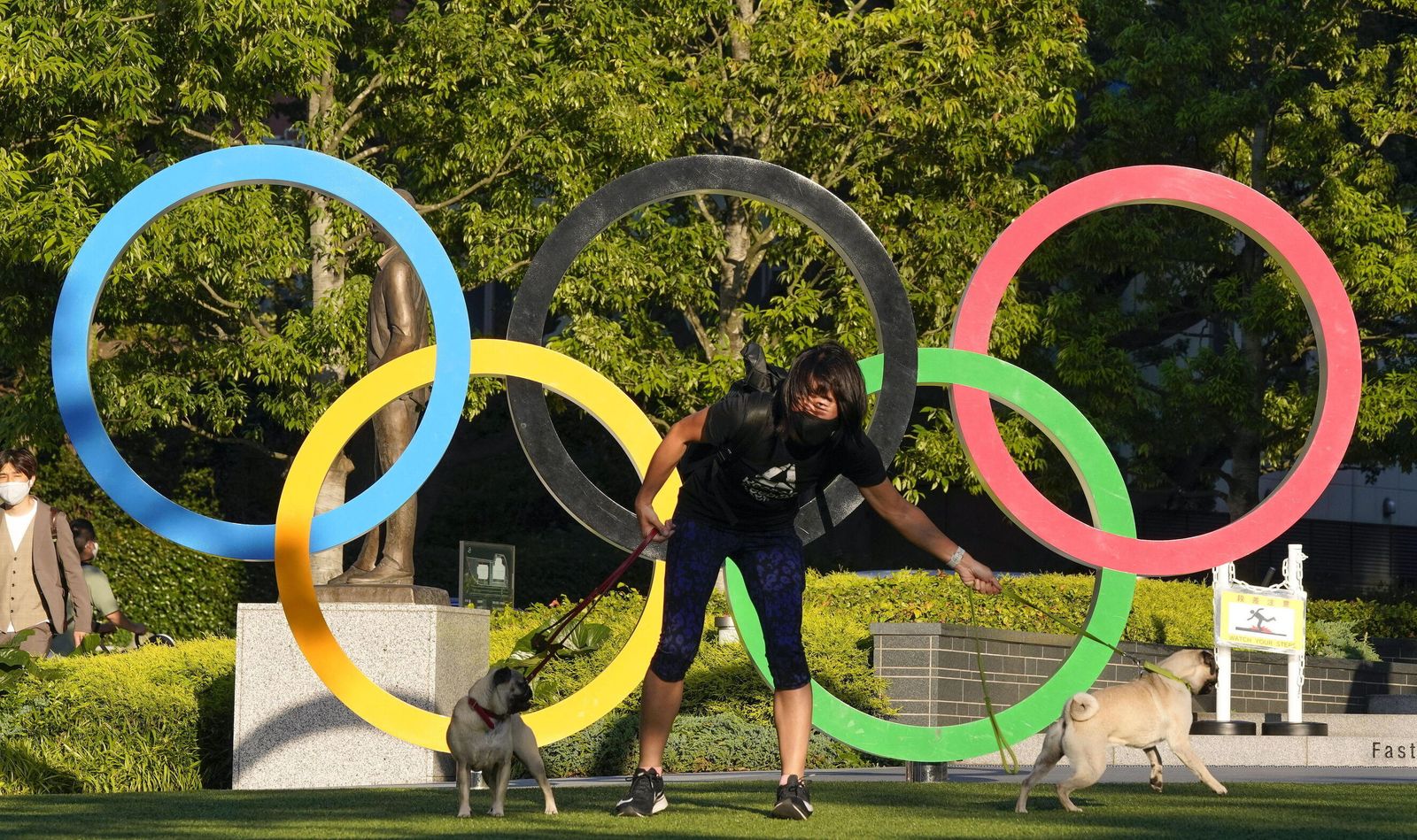 Un japonés pasea sus perros ante el logo de los JJOO.