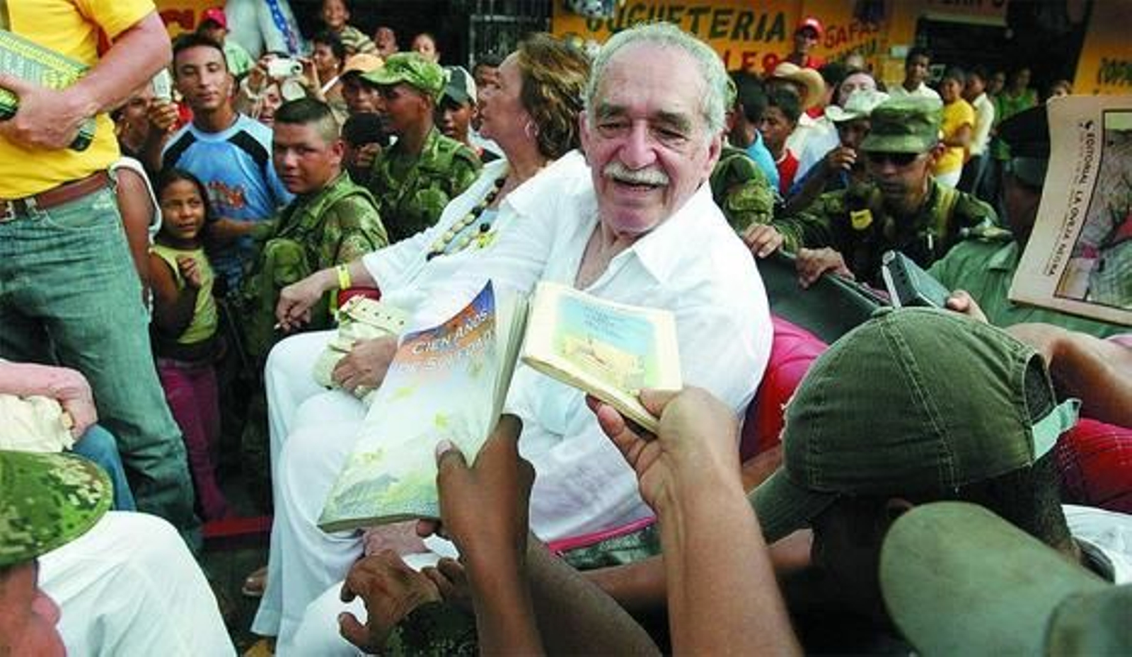 Sentado junto a su mujer, Mercedes Barcha, es solicitado por sus admiradores para pedirle un autógrafo antes de subir al tren que le llevará a Aracataca en 2007. / EFE