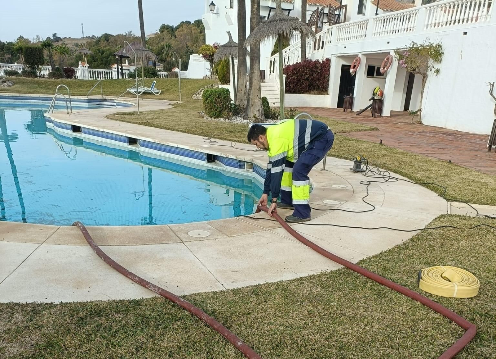 Un operario sustrayendo el agua de la piscina.