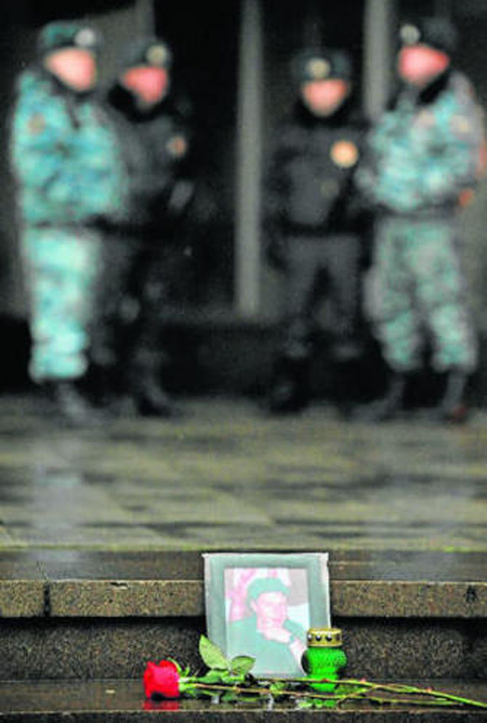 Una flor y una vela junto a la foto de una víctima ante el teatro.