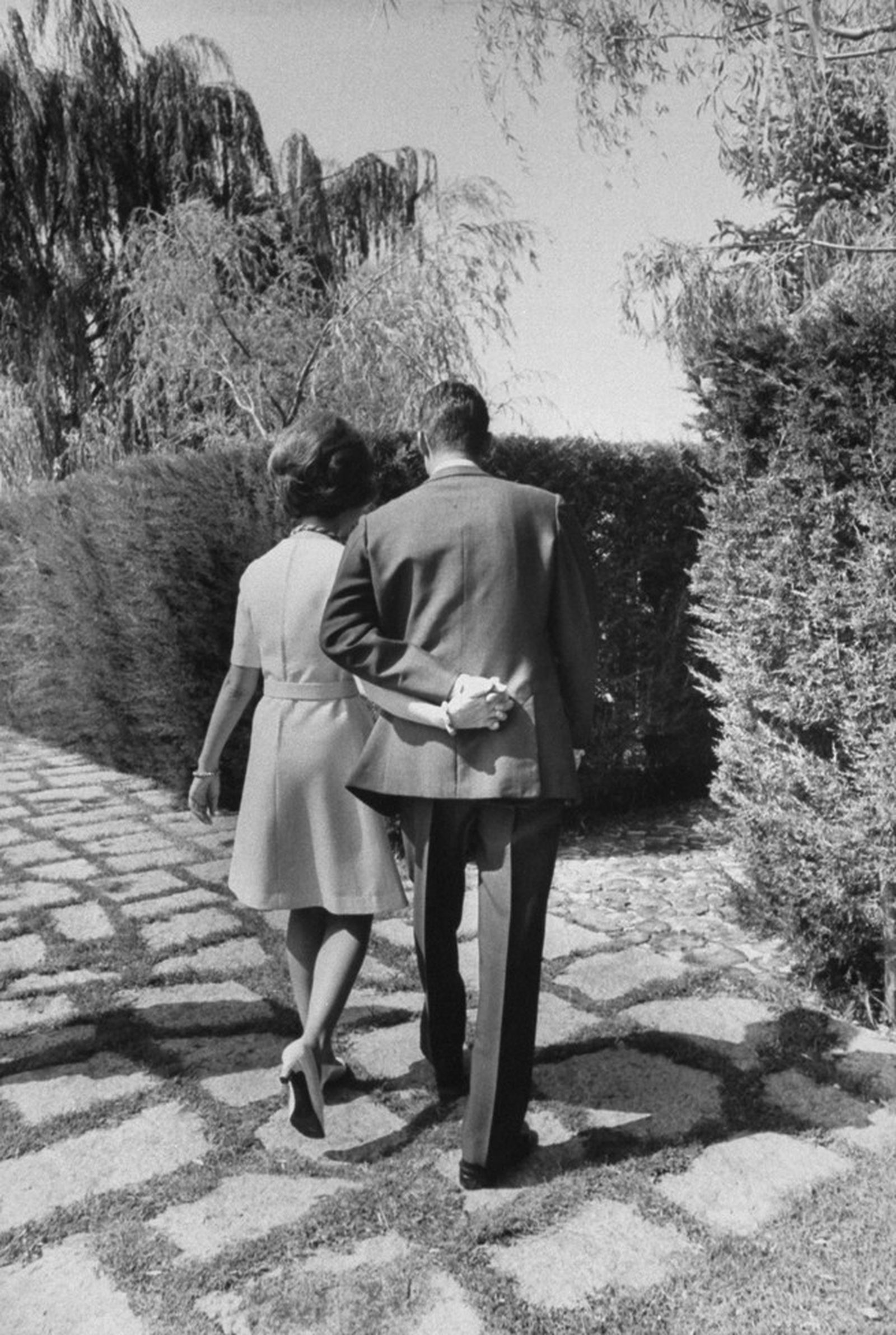 Los entonces príncipes el año 1969, abrazados de por la cintura, caminan de espaldas por los jardines de Zarzuela.