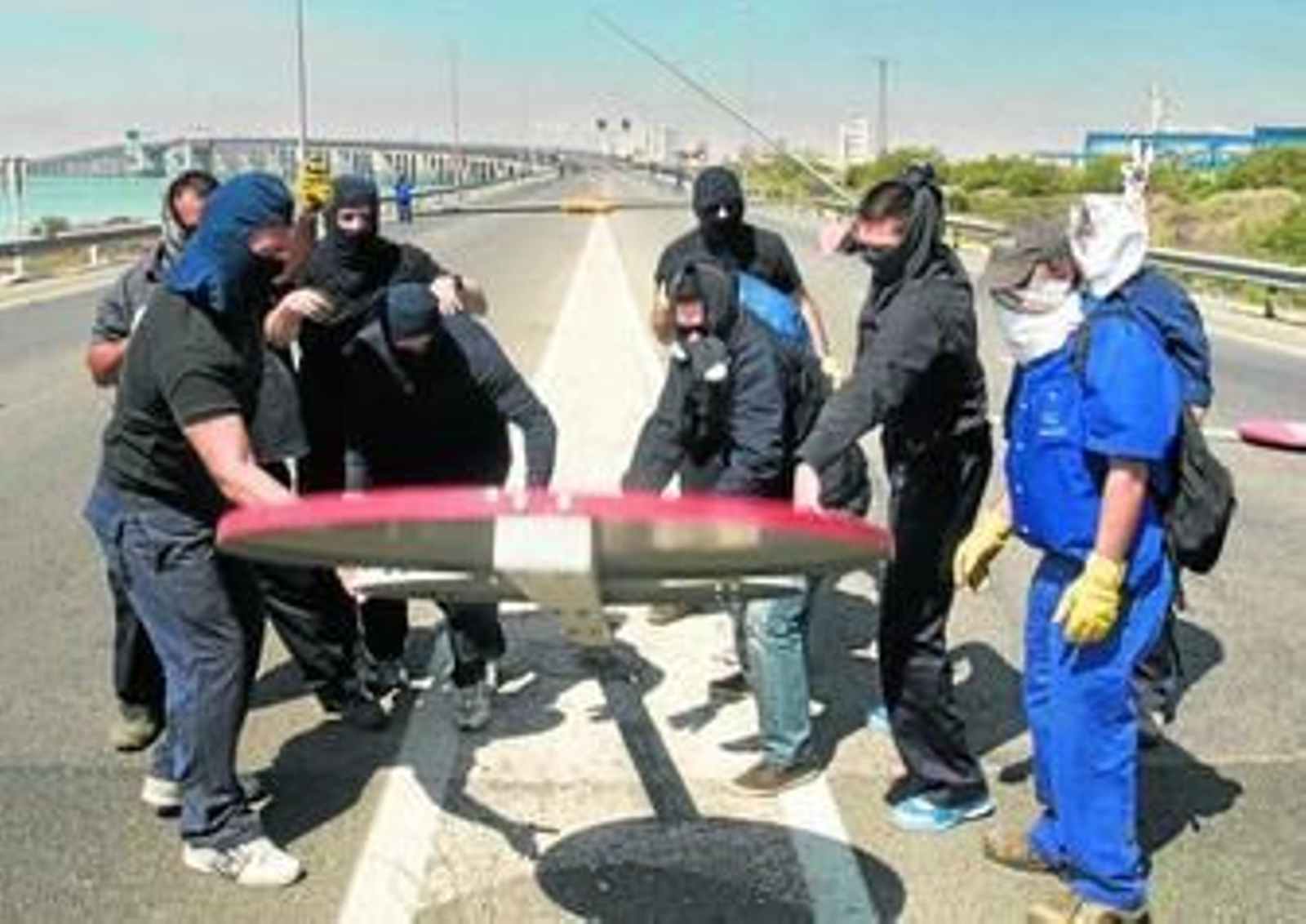 Varios operarios echan abajo una señal de tráfico junto al puente.