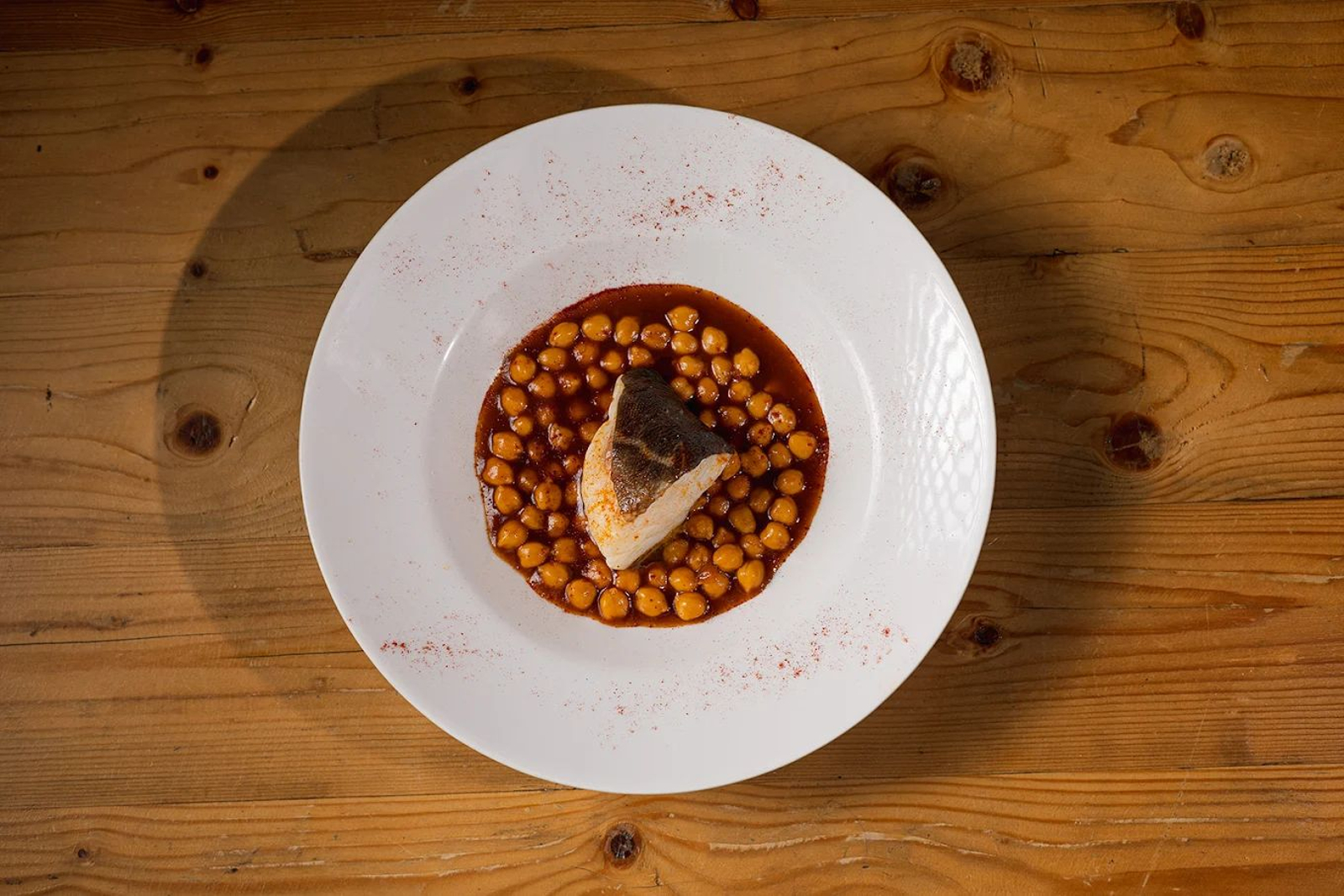 Bacalao confitado sobre guiso de manitas de cerdo y unos garbancitos.