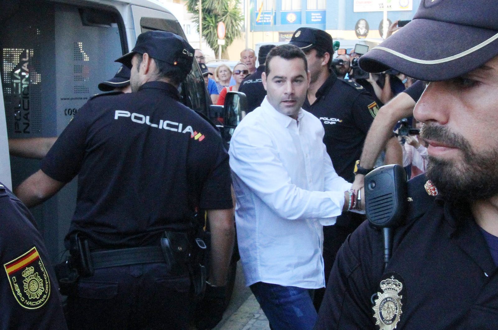 Fran Medina saluda a sus familiares en el camino que separa el furgón policial de la puerta de detenidos, ayer.