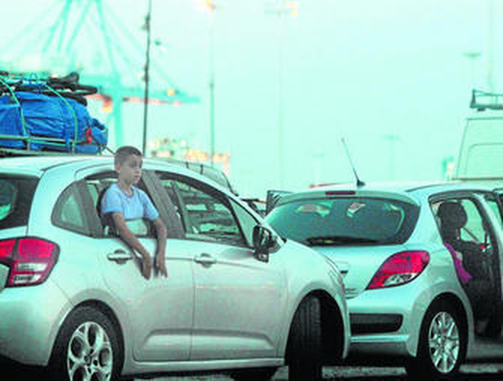 Un niño se asoma a la ventanilla de un coche en cola para embarcar en el puerto de Algeciras.