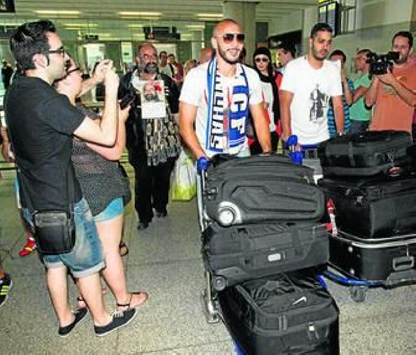 Nordin Amrabat, ataviado con una bufanda malaguista, llega a la terminal del aeropuerto de Málaga.