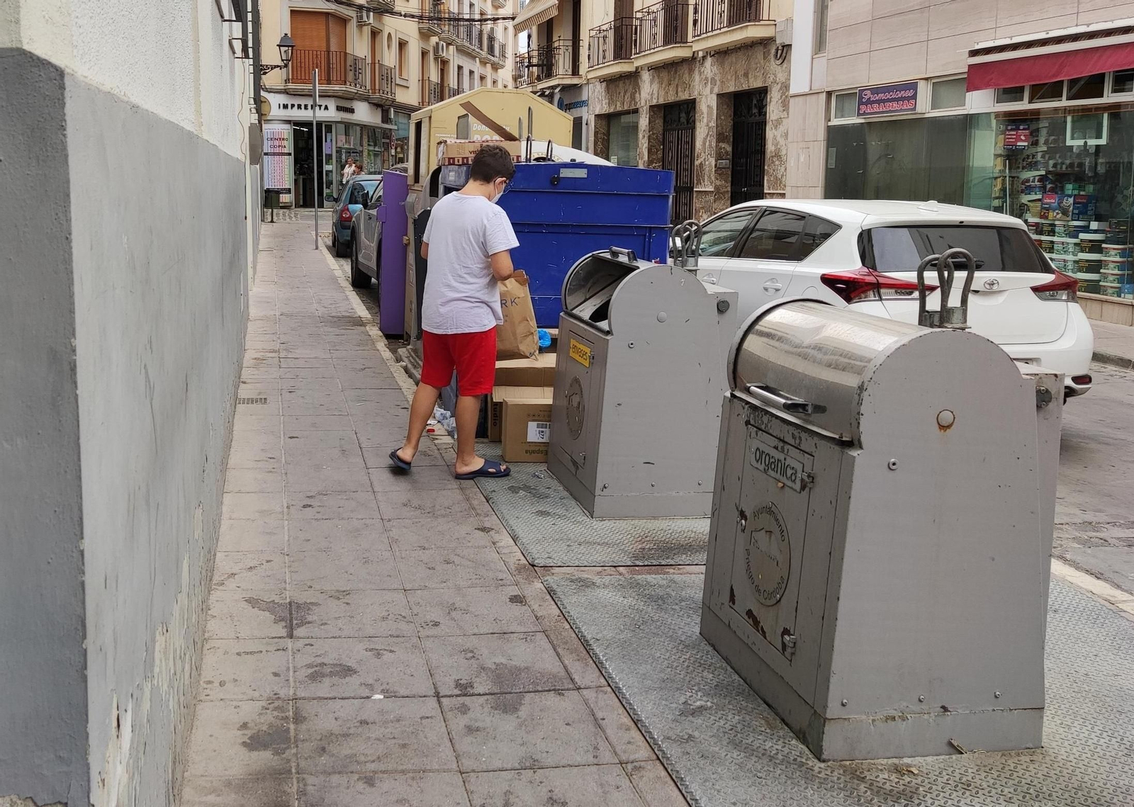 Un joven deposita basura en un contenedor.