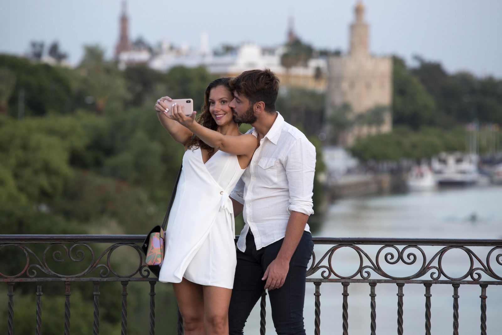 Una pareja se hace un selfi en el puente de Triana con la torre del Oro al fondo.