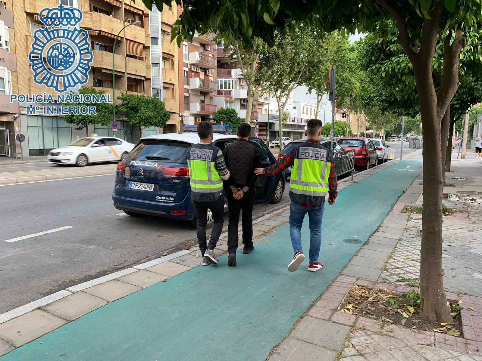 Dos policías trasladan al sospechoso, en la puerta de la comisaría de Nervión.