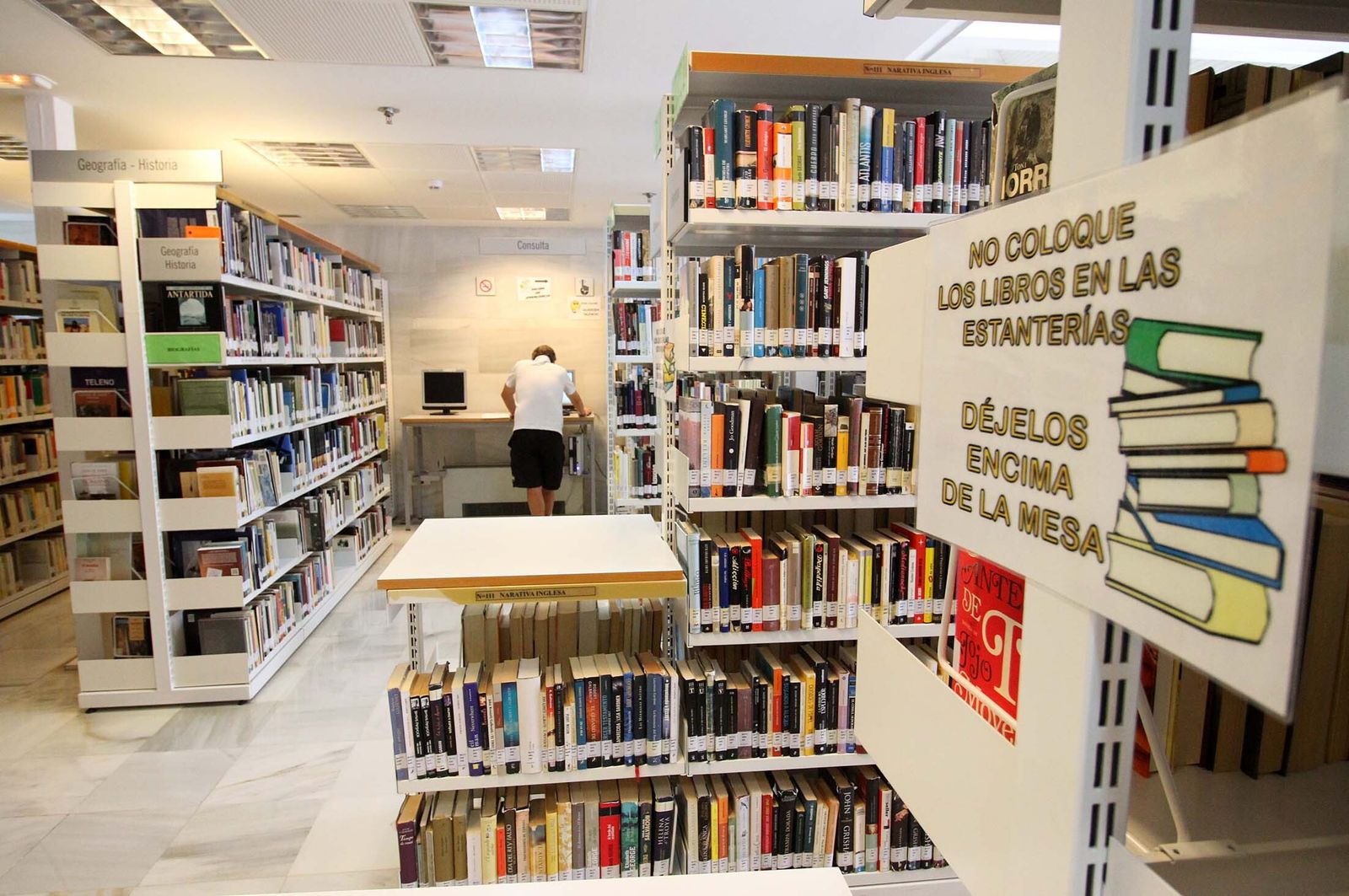 Un hombre busca ejemplares en el interior de una biblioteca.