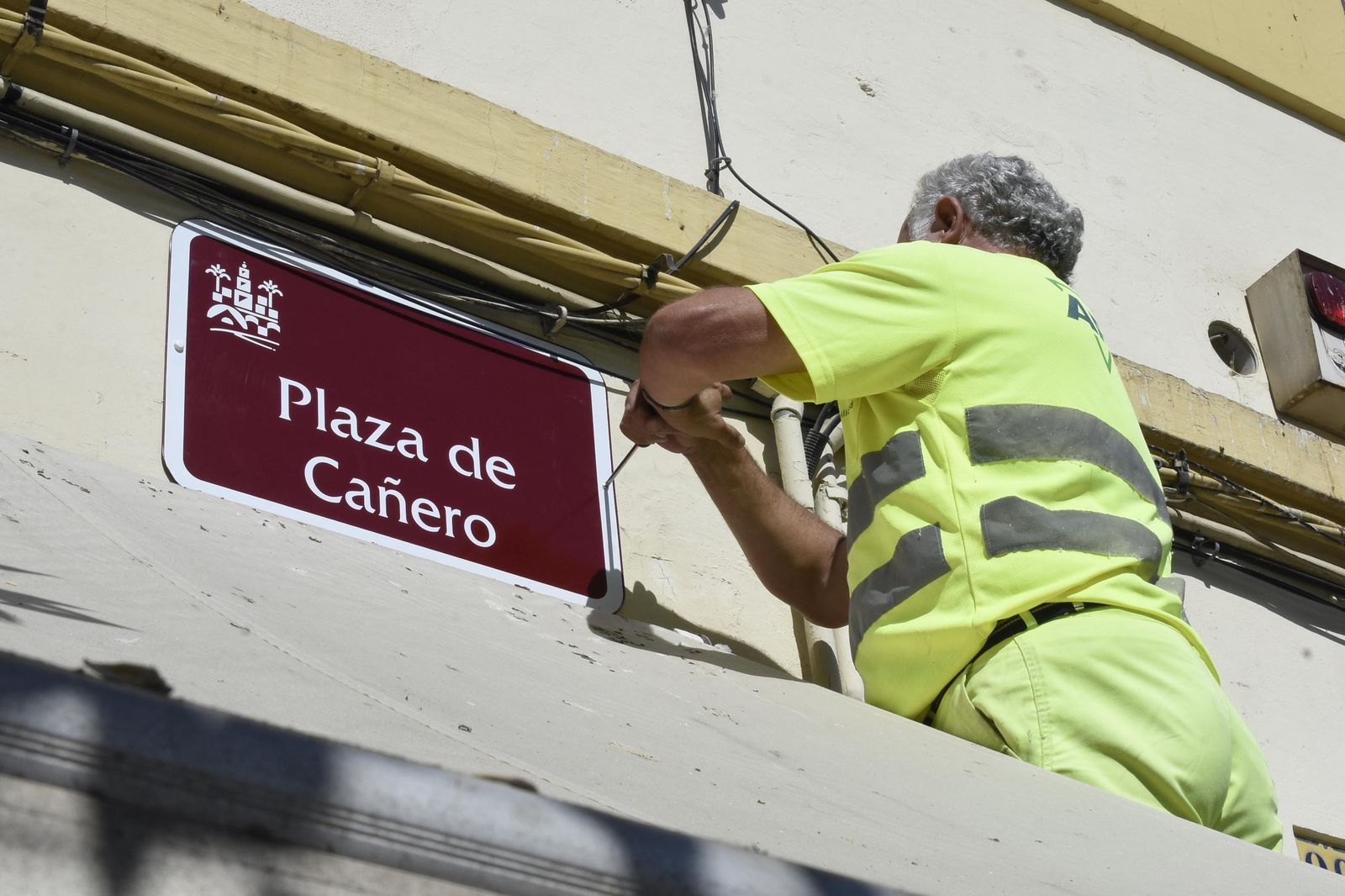 Un operario vuelve a colocar el rótulo de plaza de Cañero.