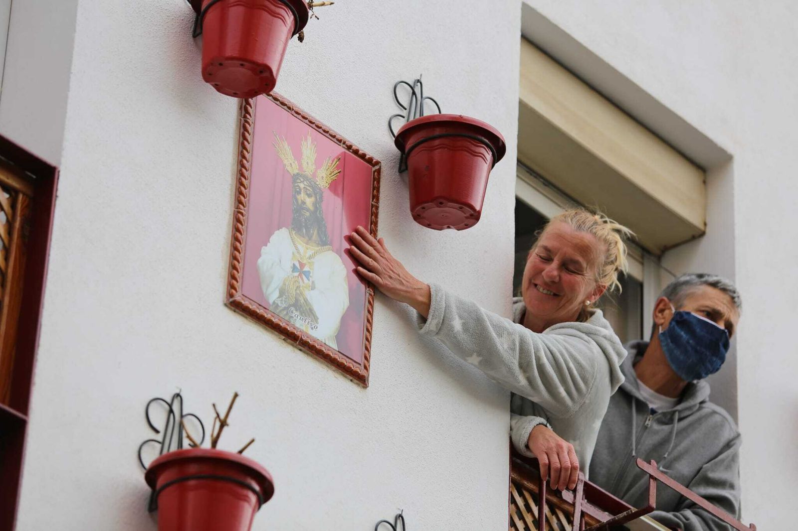 Una mujer acaricia la imagen de Jesús Cautivo en su balcón