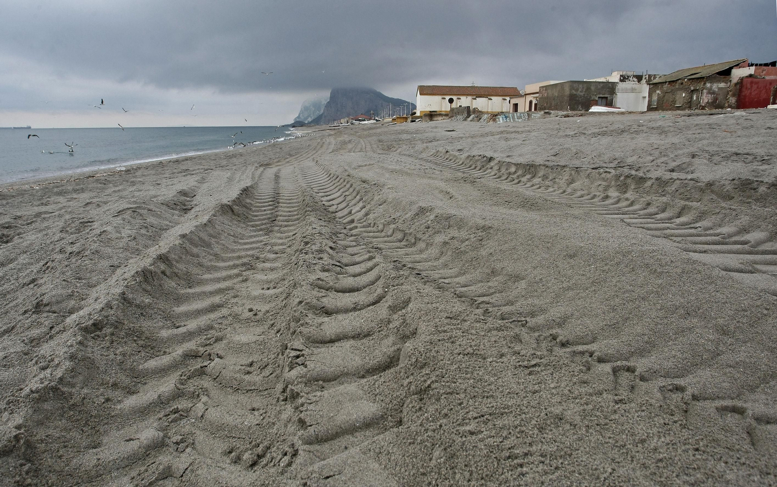 Marcas de neumáticos en la playa del Tonelero, junto a las viviendas.