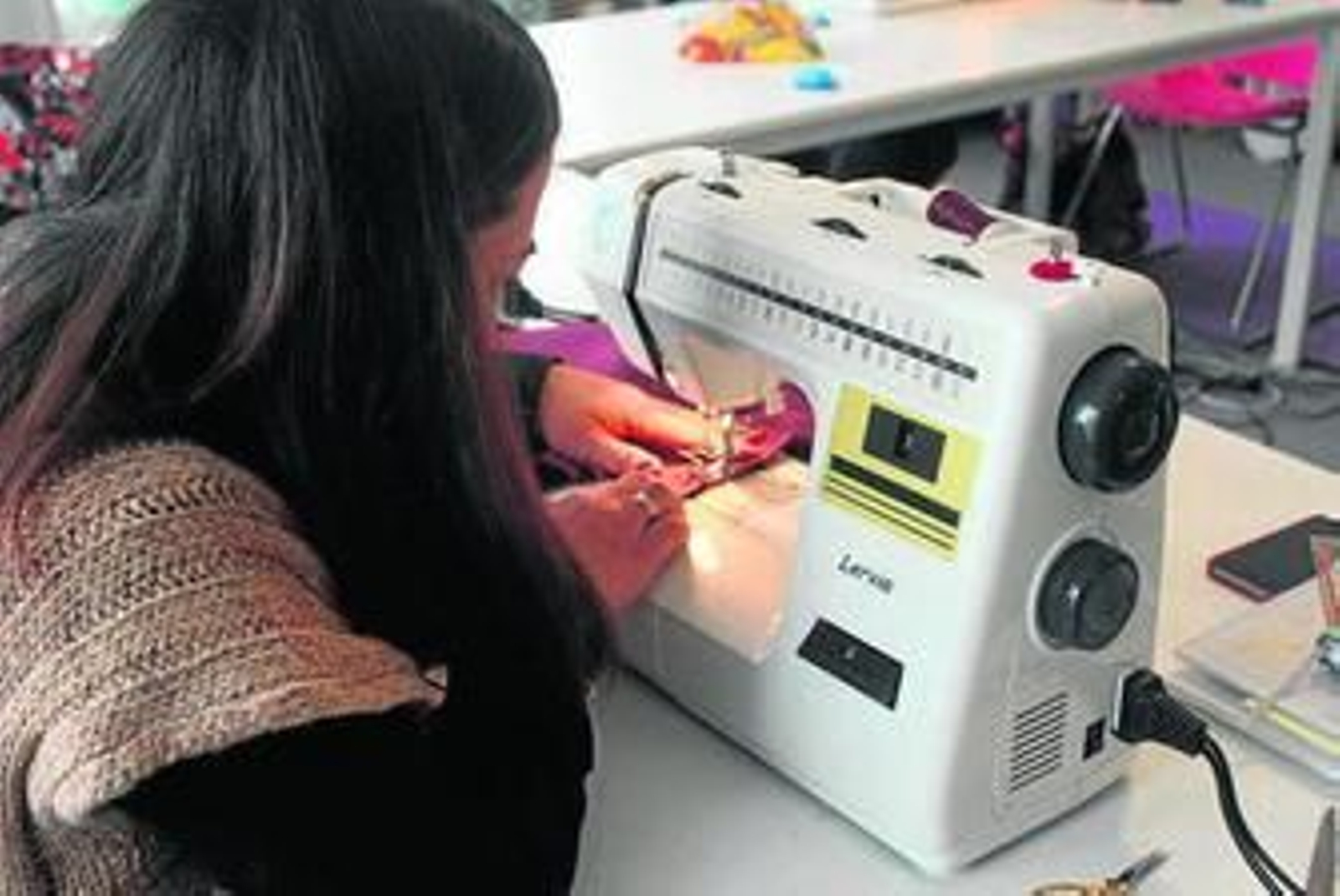 Una de las alumnas aprende a manejar su máquina de coser.