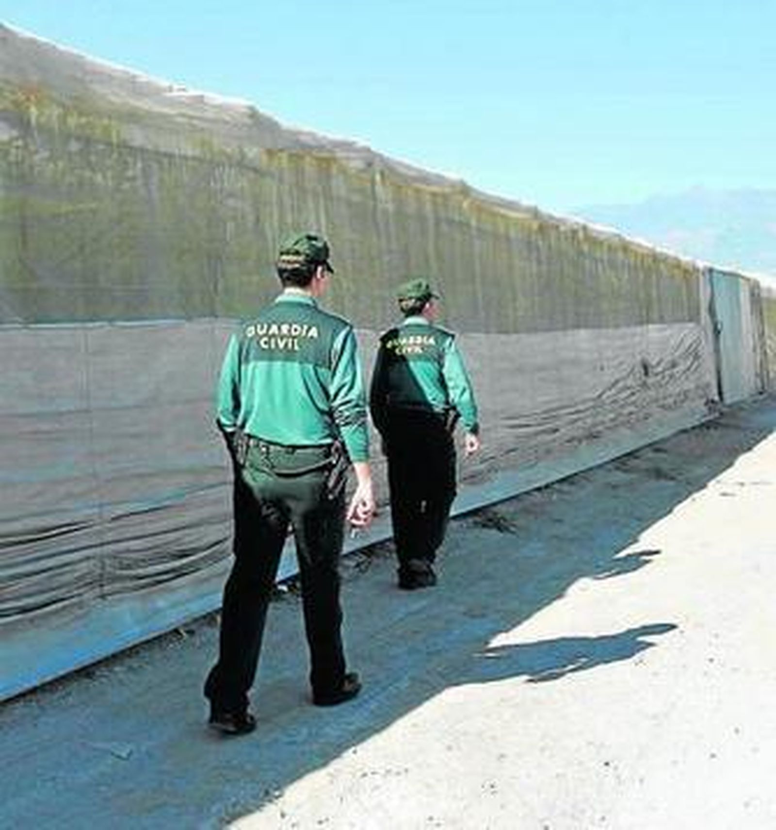 Dos agentes de la Guardia Civil junto a un invernadero.