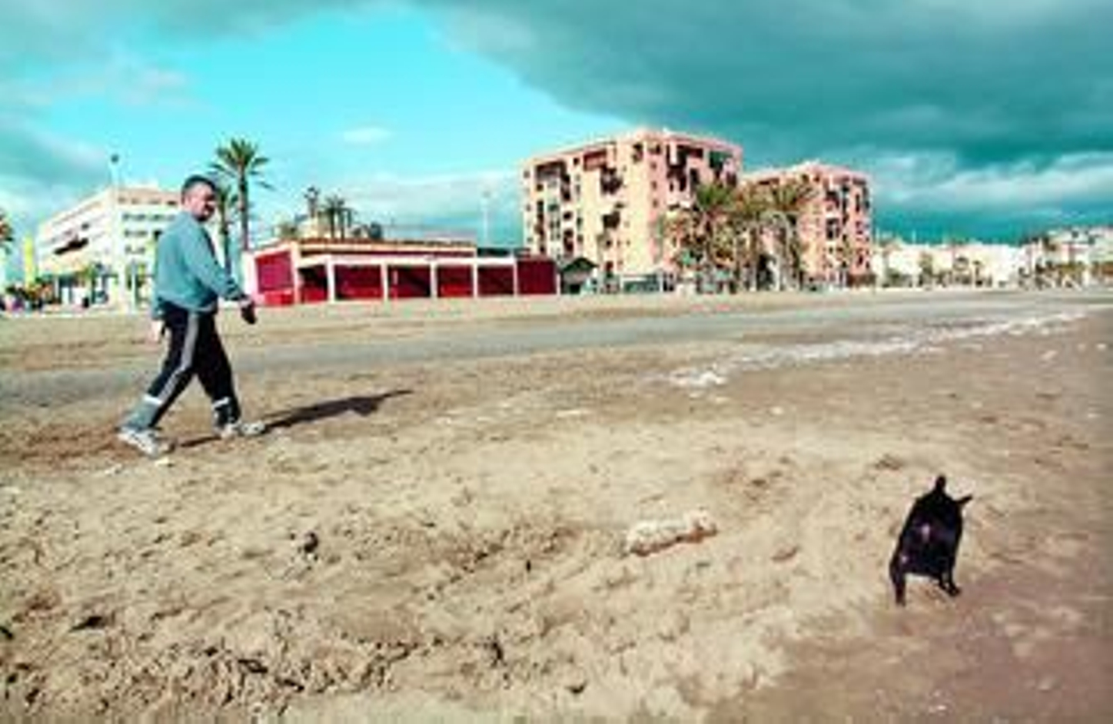 Un hombre pasea por la playa junto a su perro justo en el punto donde se encontró el cadáver.