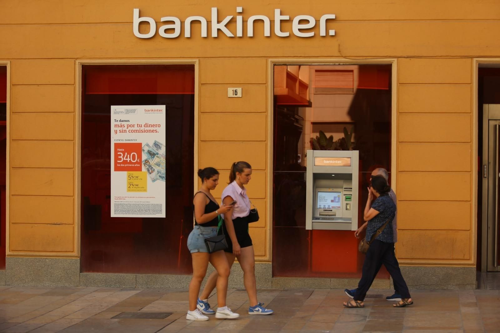 Varias personas pasan junto a una oficina de Bankinter en Málaga. Varias personas pasan junto a una oficina de Bankinter en Málaga.