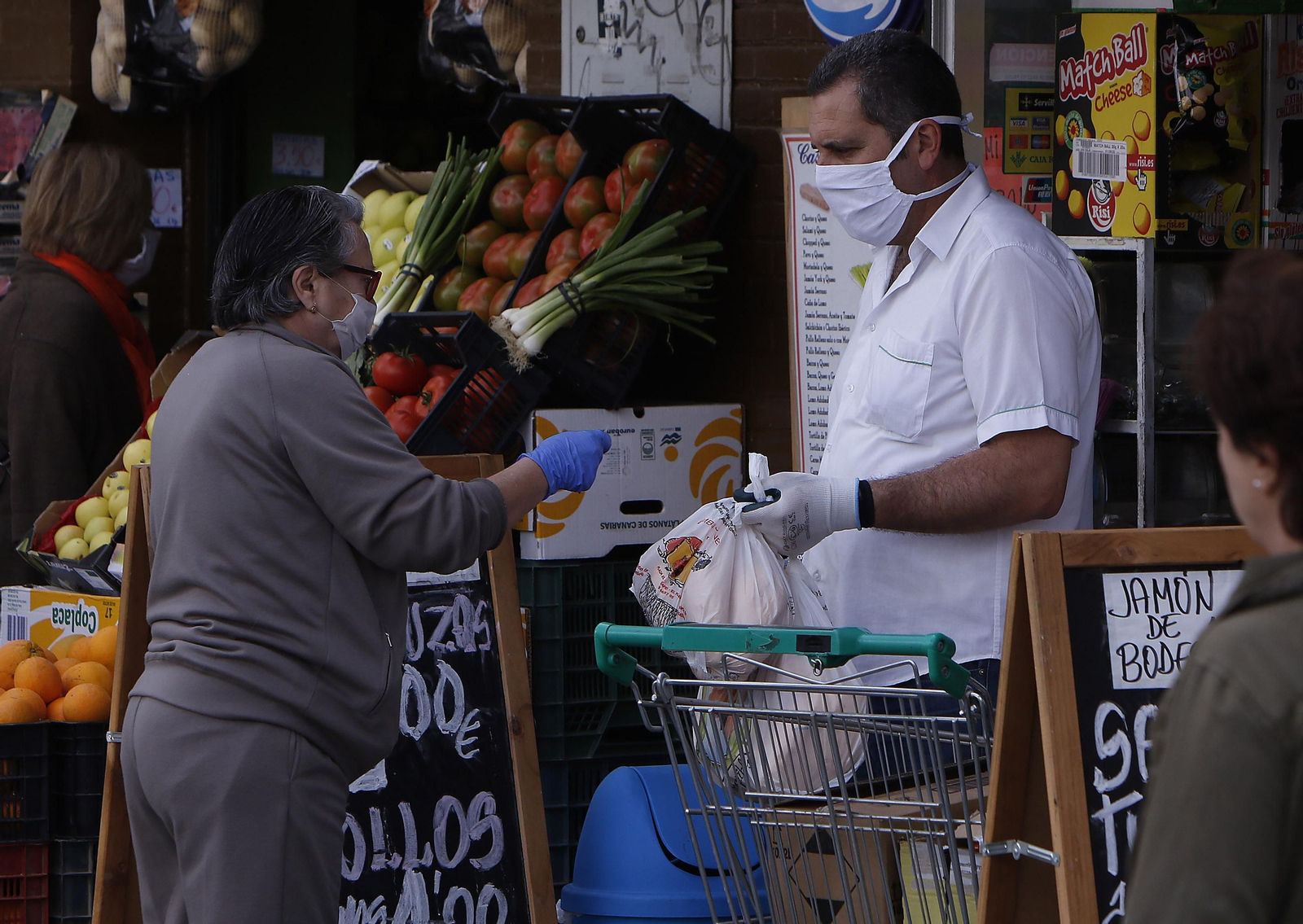 El empleado de una frutería atiende a un cliente con mascarilla en la calle durante el confinamiento de 2020.