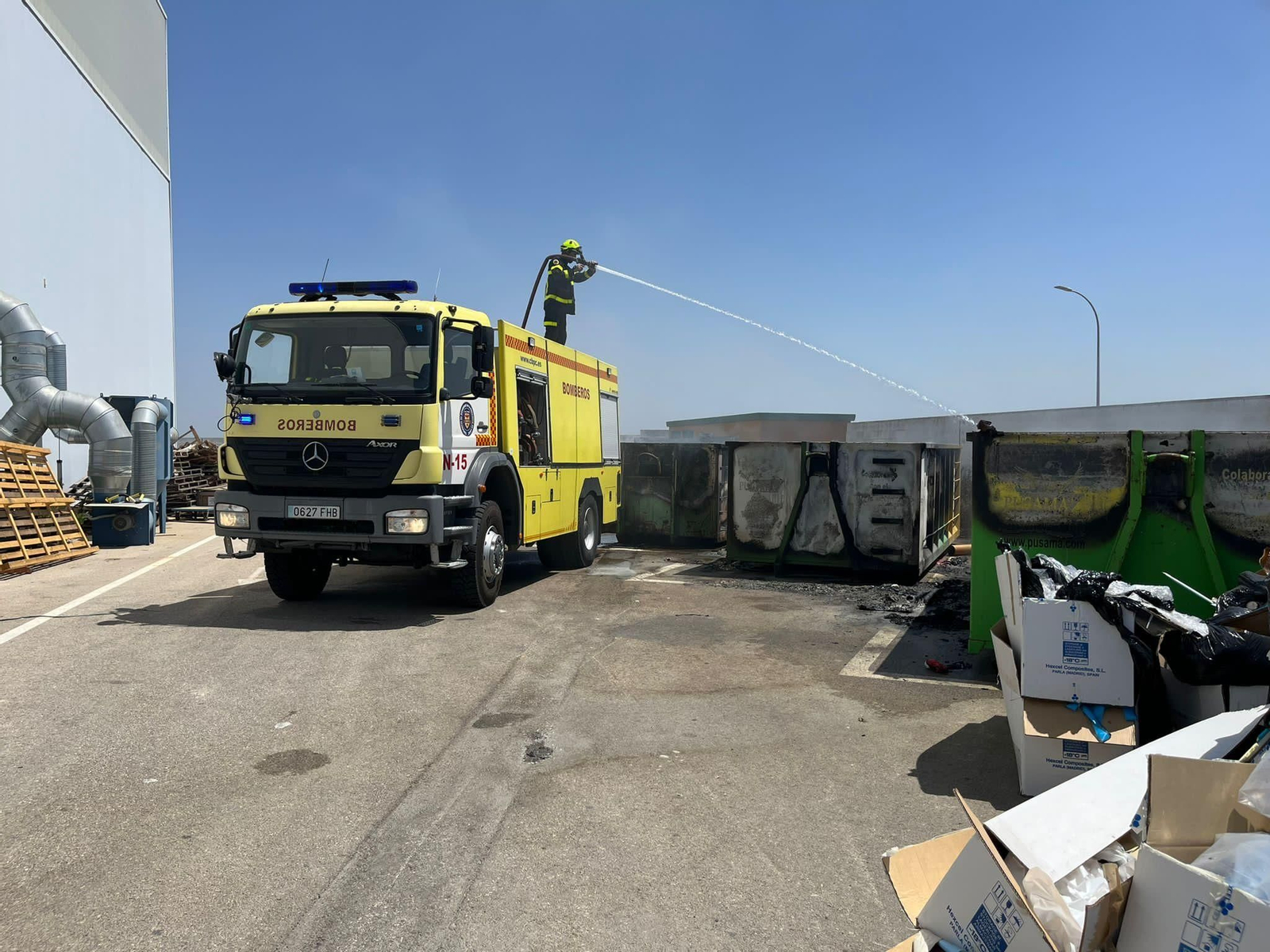 Bomberos actuando en la extinción del incendio originado en el interior del contenedor.