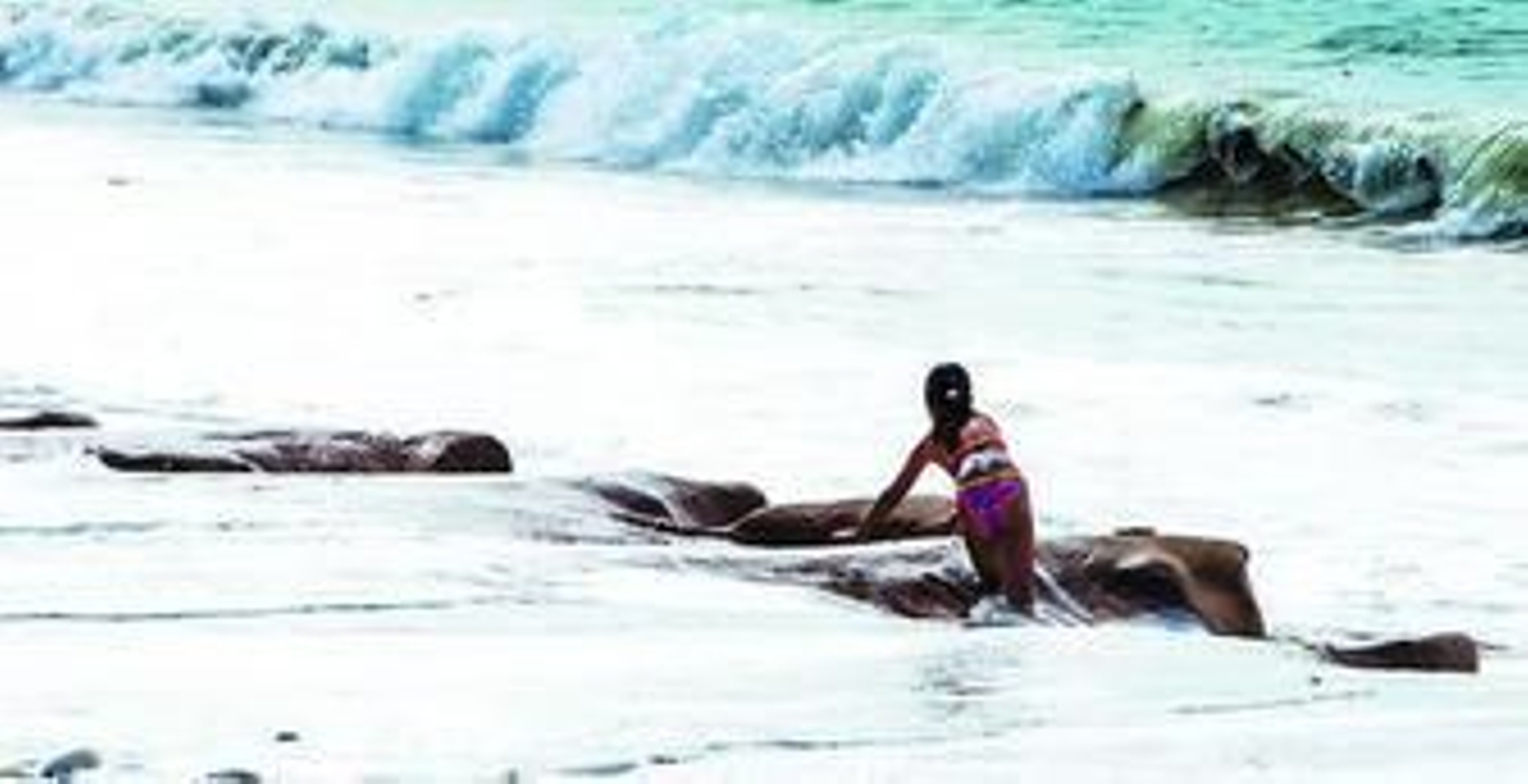 Una niña salva la altura del escalón  para acceder a la orilla en la playa de Santa María del Mar.