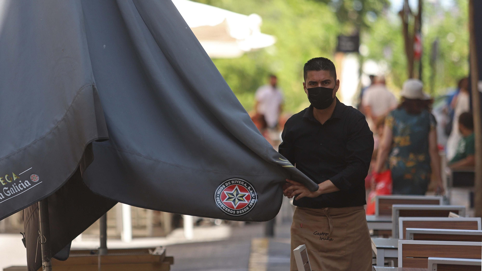 Un camarero con mascarilla instala una terraza en Algeciras.