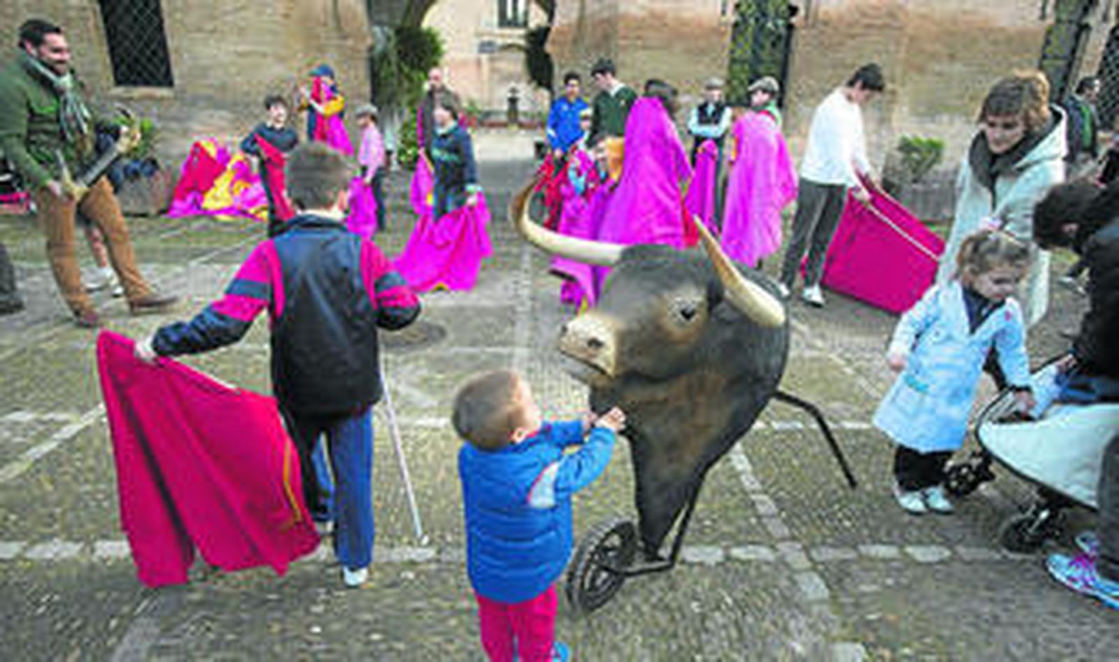 Un niño acaricia la badana de la cabeza de toro de un carretón, entre tanto otros esbozan capotazos y muletazos.