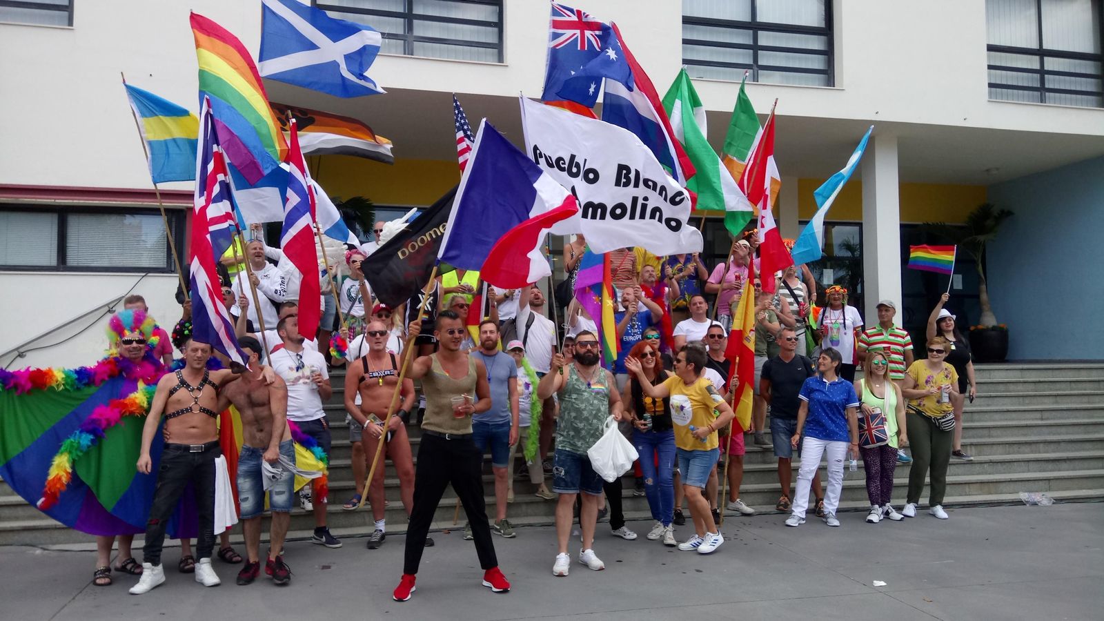 Participantes en el evento ondean banderas multicolores ante el Ayuntamiento.