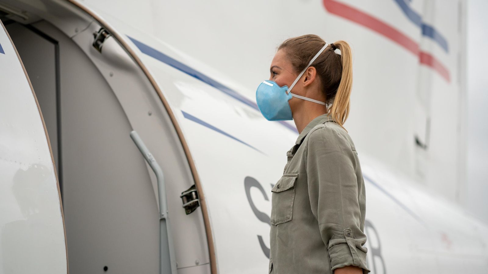 Una joven a punto de entrar en un avión con la mascarilla FFP2 bien ajustada a su cabeza