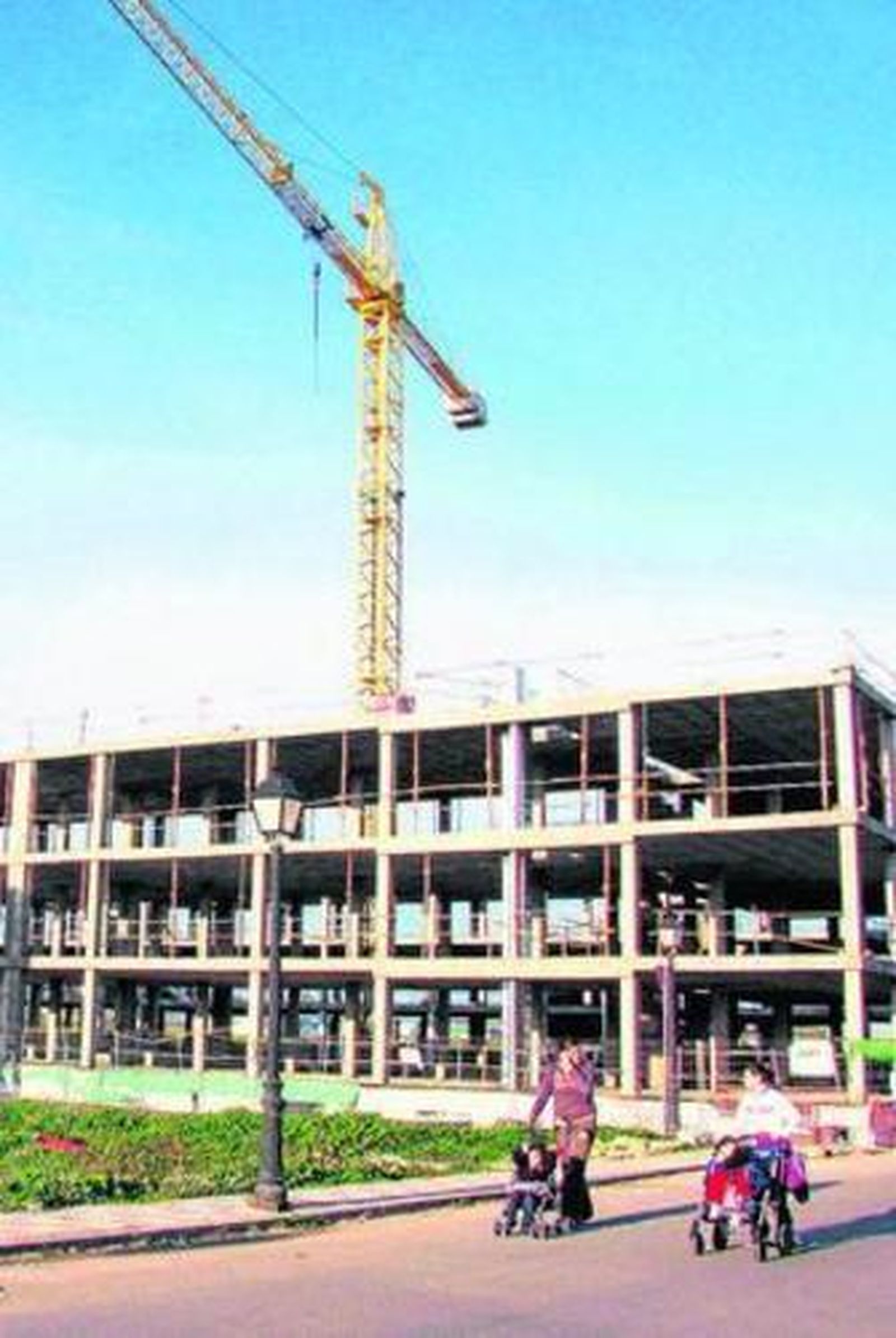 Dos mujeres pasean, junto a sus hijos, al lado de una construcción.
