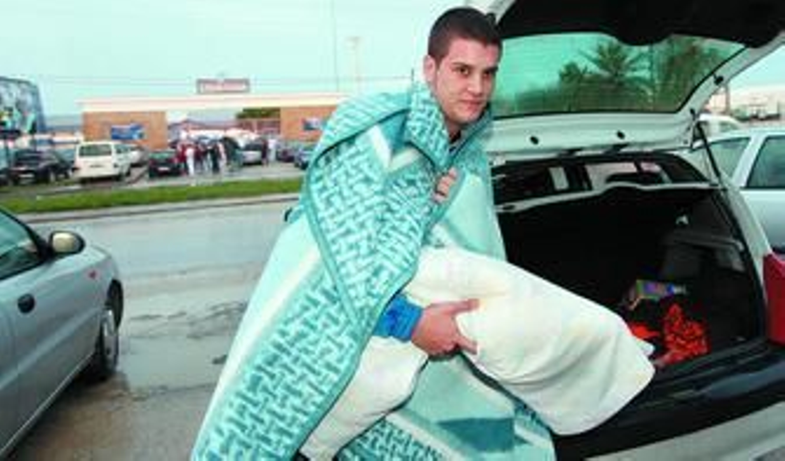 Un joven se dispone a guardar manta y almohada en el maletero de su coche, después de pasar una noche a las puertas de Cojetusa, ayer.
