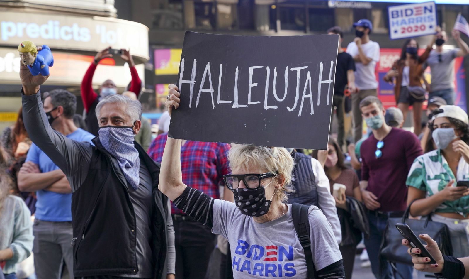 Una mujer levanta una pancarta en las calles de Nueva York durante una de las celebraciones espontáneas que se registraron ayer tras conocerse la victoria de Joe Biden.