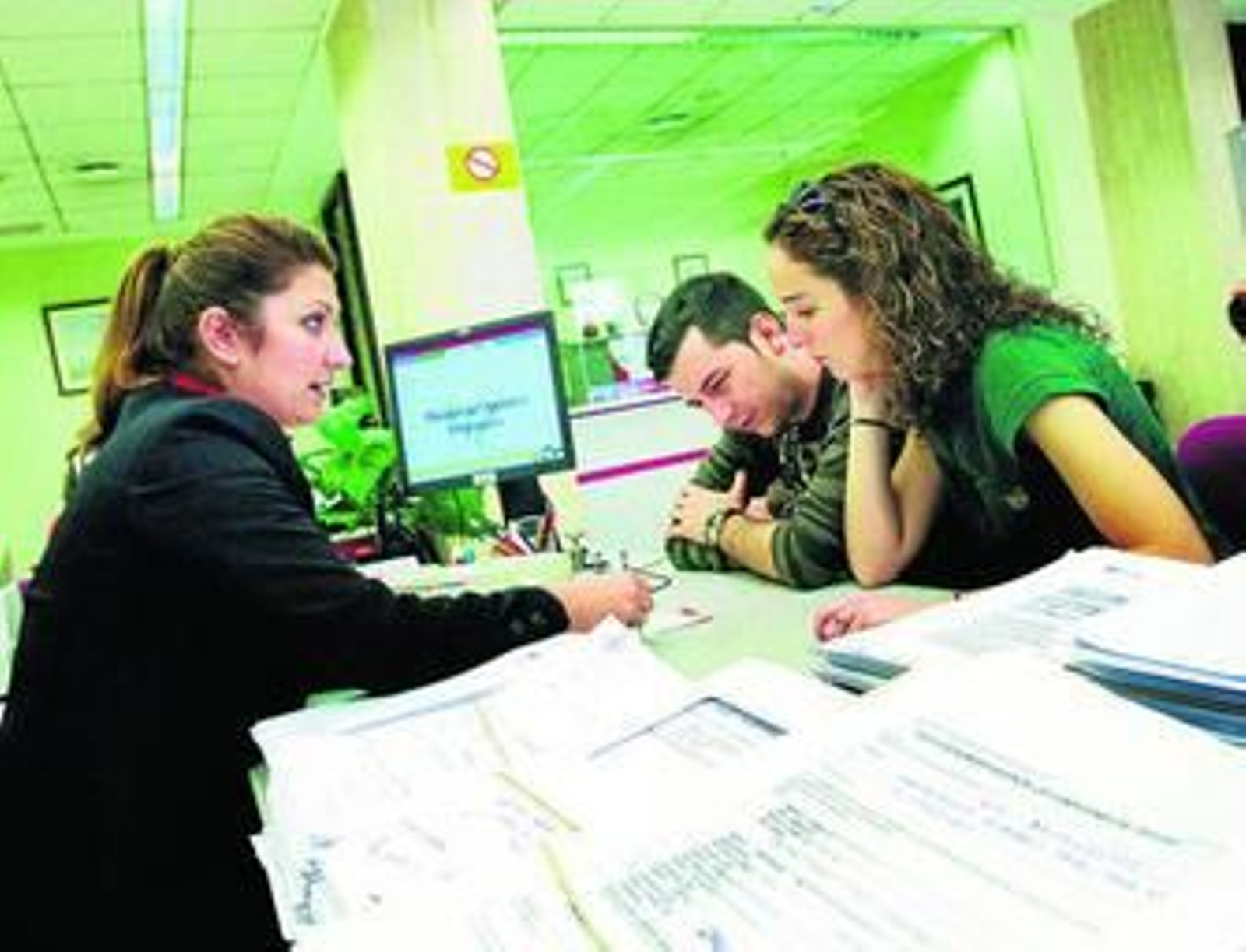 Una pareja de jóvenes se interesa por las condiciones de una hipoteca en un banco.