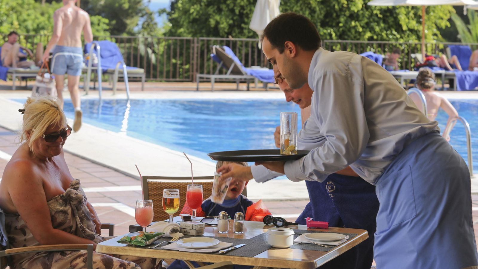 Un camarero atiende a unos turistas en un hotel en la Costa del Sol.