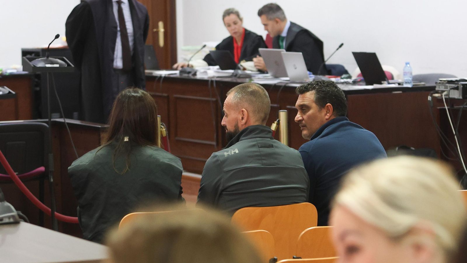 Pedro Maza habla con su abogada en presencia de otro acusado en un receso.