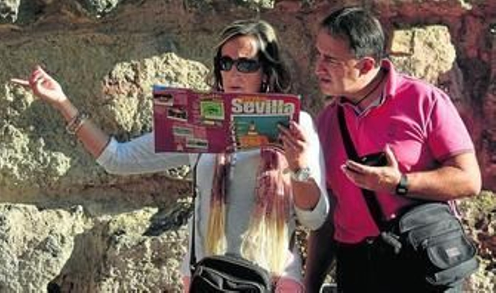 Dos turistas intentan averiguar un detalle en una guía sobre la ciudad.