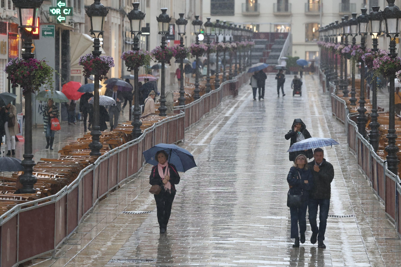 Viandantes recorren la calle Larios bajo la lluvia esta Semana Santa 2024.