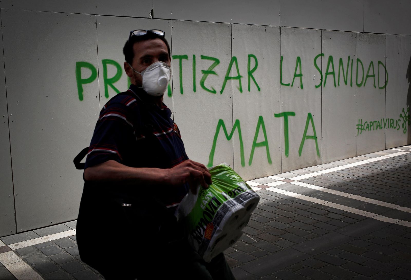 Un hombre pasa ante una pintada con una mascarilla