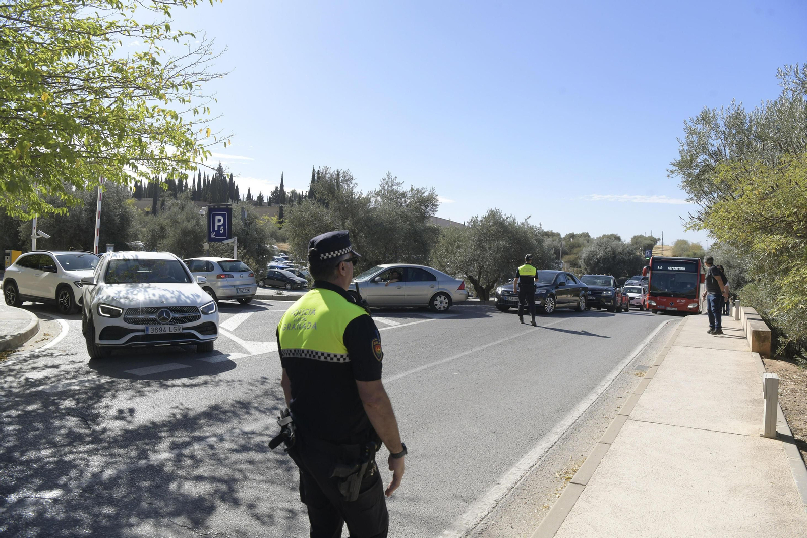 Agente de la Local regula el tráfico en el parking del cementerio de Granada, en una imagen de archivo.