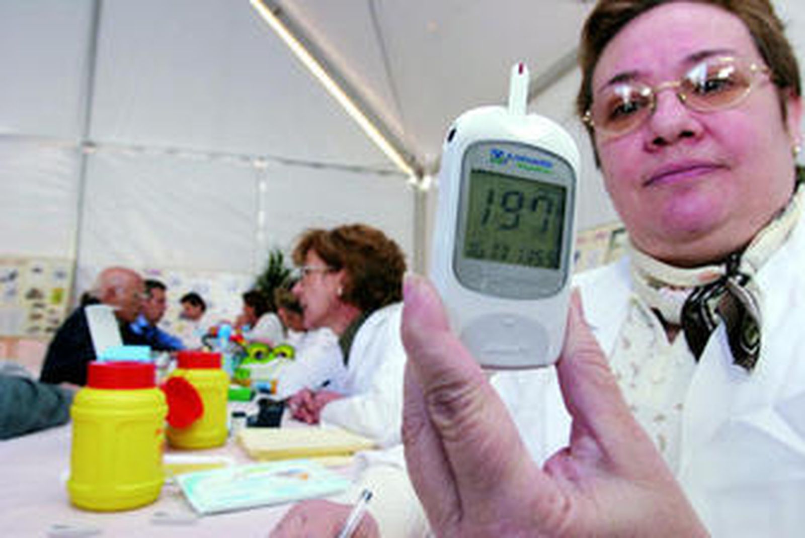 Una señora muestra el aparato para hacerse la prueba del azucar.