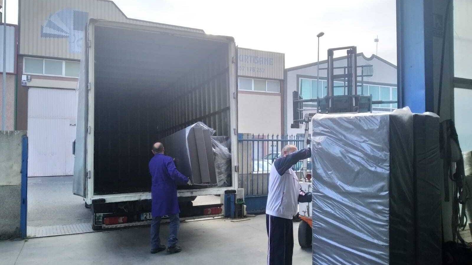 Los operarios cargan los colchones para su reparto.