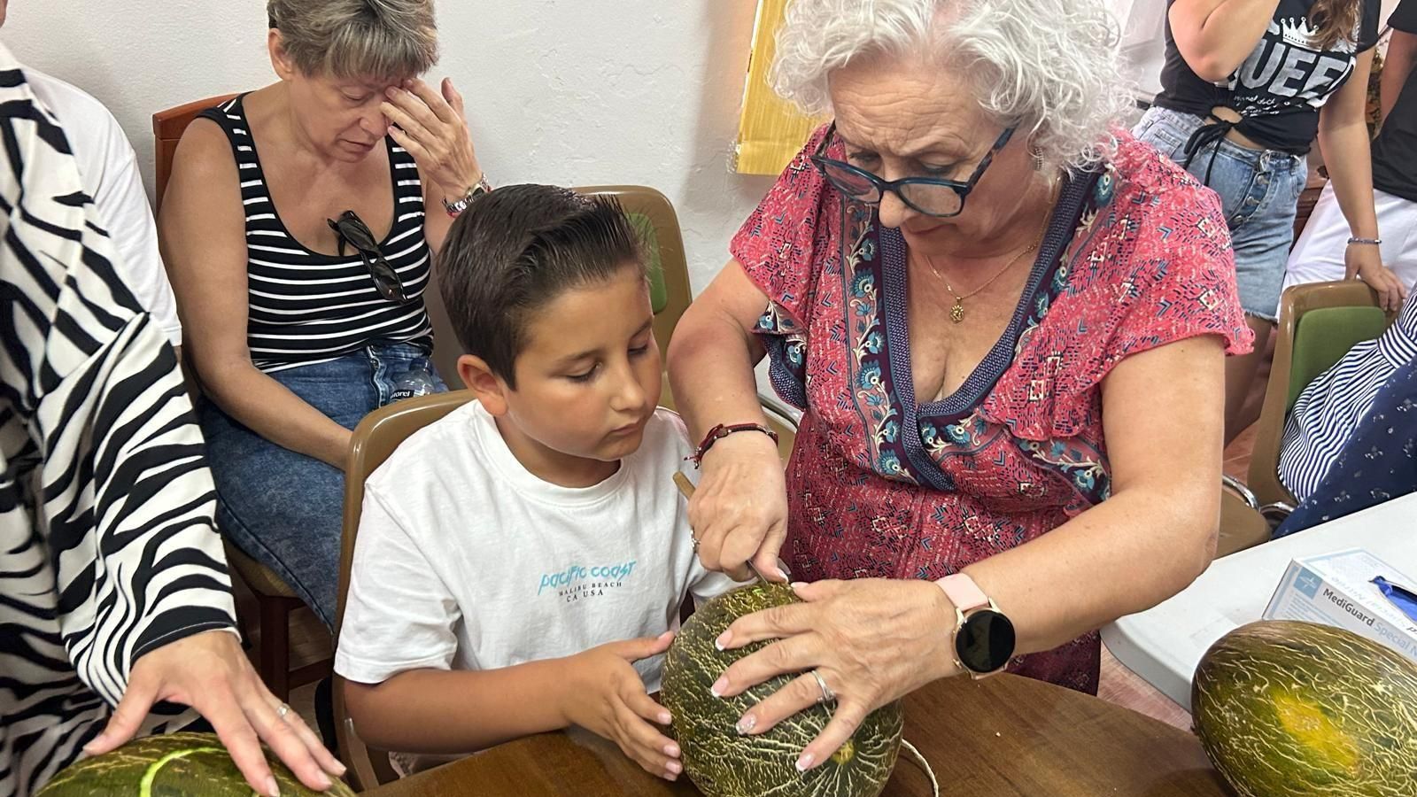 Los mayores trazan los dibujos sobre la piel del melón.