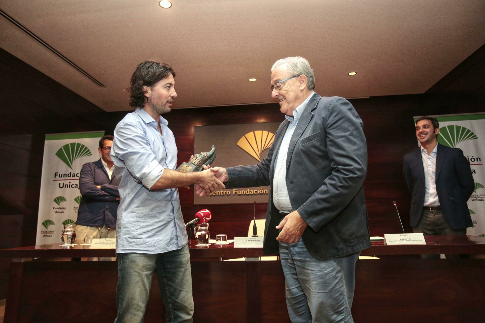 El periodista Ricardo F. Colmenero (izquierda) recoge el premio de manos de Mariano Vergara, vicepresidente de la Fundación Unicaja.