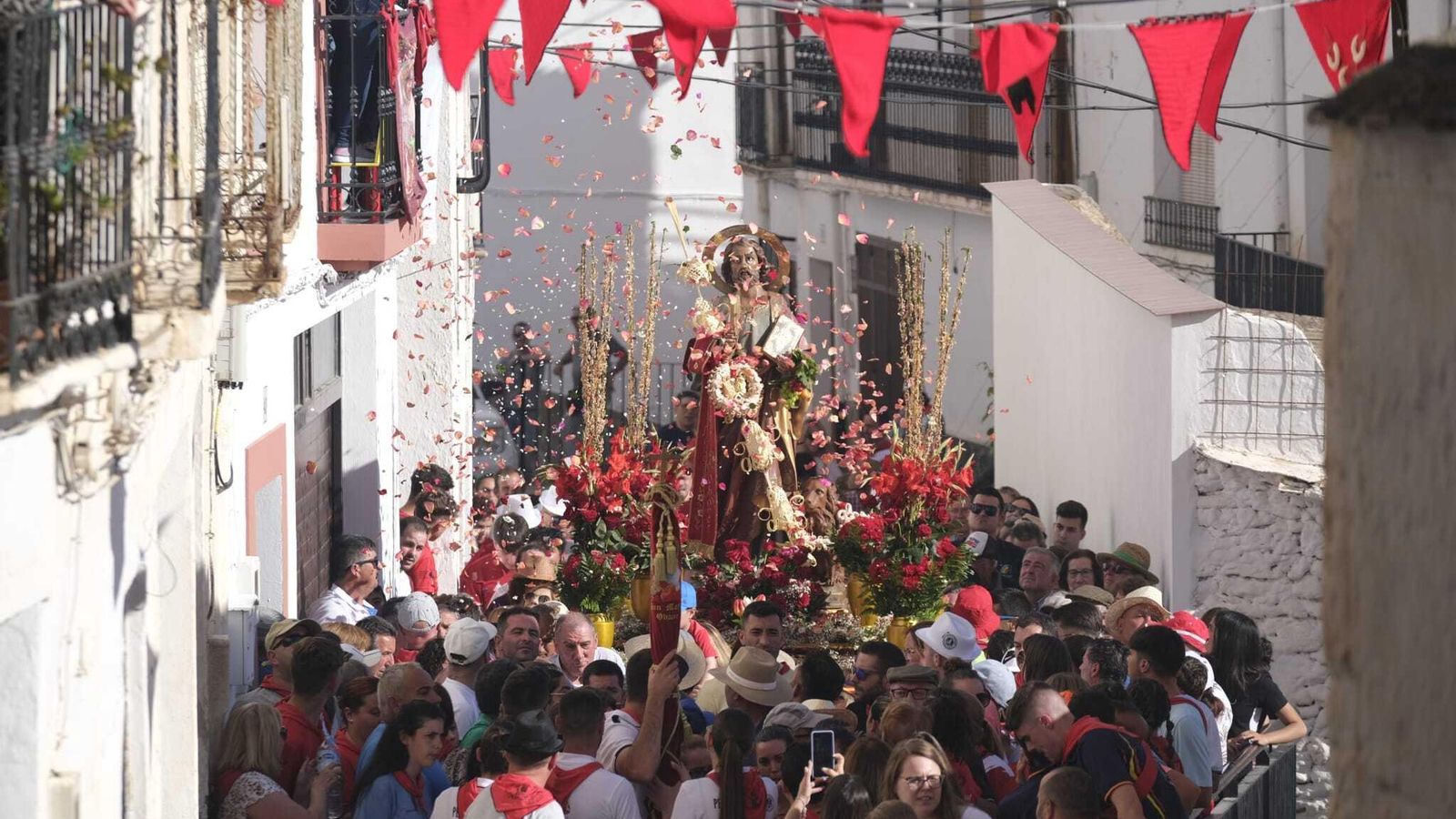 Lanzamiento de pétalos de flores al paso de la imagen por las estrechas calles de Ohanes.